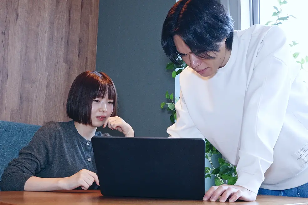 PCを見ながら相談し合う2人の社員